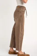 Pantalón jean de corte barrel y tiro alto, en tono marrón lavado, con bolsillos laterales y traseros, y lazo ajustable en la cintura.