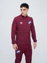 Campera deportiva Umbro del Club Nacional de Football, modelo Grok, en color bordó con diseño estampado sutil. Cuenta con cierre frontal completo, cuello alto y bolsillos laterales.