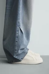 Zapatilla negra de cordones, con parte superior lisa y cordonera oculta. Posee suela con volumen a tono.