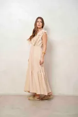 Vestido largo color beige, sin mangas, con escote en V cruzado, detalles de volados con encaje en los hombros, cintura elastizada fruncida y falda larga con vuelo.