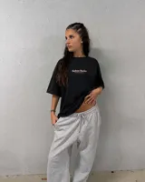 Remera oversize negra con diseño gráfico en la espalda que incluye la inscripción "Kaboa Radio" y un personaje ilustrado, de corte amplio y mangas cortas.