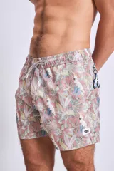 Short de baño con estampado botánico en tonos tierra, rosados y verdes. Presenta cintura elástica con cordón ajustable y un pequeño parche con logo en el ruedo.