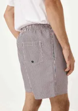 Short de baño blanco con estampado de hojas negras, cintura elástica y bolsillos laterales.