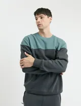 Sweater de tejido circular con diseño color block, combinando una franja superior en color verde y el resto de la prenda en gris oscuro. Presenta cuello redondo y puños en tejido canalé.