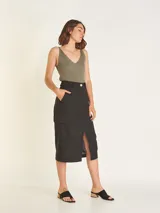 Falda midi color beige, de tiro alto con elástico en la cintura trasera, cierre y botón delantero. Tiene bolsillos delanteros y bolsillos cargo a los costados, con tajo en el delantero.