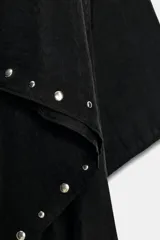 Capa negra de cuello redondo con detalle de tachas plateadas en el ruedo y pañuelo tipo bufanda integrado en el mismo tejido.