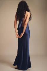 Vestido largo de satén azul marino con cuello halter y espalda descubierta. Presenta un cierre posterior con cremallera oculta y lazada en el cuello.