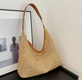 Cartera tipo hobo de tejido de yute en color beige, con asa larga de cuero sintético en color marrón.