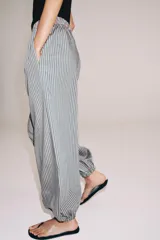 Pantalón de tiro medio con pierna ancha y cintura elástica, confeccionado en mezcla de viscosa con diseño de rayas verticales en tonos mostaza y marrón.