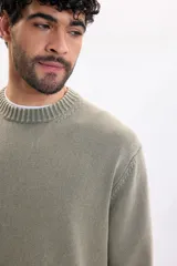 Buzo tejido lavado de color verde militar, con cuello redondo, mangas largas y puños y cintura de rib elástico.