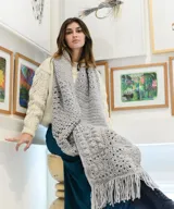 Chal oversized tejido a mano en técnica crochet con lana merino, color gris, con diseño texturizado de granny square y largos flecos en los extremos.