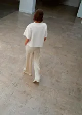 Pantalón de tiro medio confeccionado en tejido satinado de corte recto y largo, con bolsillos laterales, aberturas en el bajo y detalle de costuras.