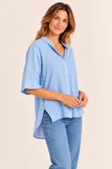 Blusa celeste de corte recto, con cuello mao y escote en V, mangas tres cuartos y diseño holgado.