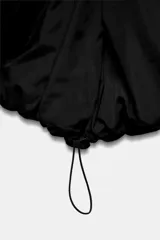 Anorak acolchado de corte corto en color negro, con capucha ajustable, cierre frontal de cremallera y bolsillos laterales. Cuenta con puños interiores y bajo ajustable con cordones elásticos.