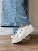 Zapatillas blancas de cuero con detalles en cuero gamuzado color beige en la puntera y ajuste con velcro. Presenta detalle de cuero con estampado reptil en el talón.