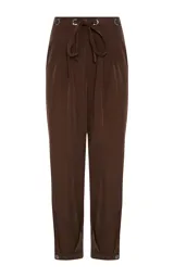 Pantalon de corte holgado color marrón, con cintura elástica ajustable mediante cordón, bolsillos laterales y puños abotonados en el bajo.