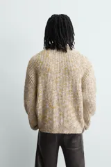Jersey de punto con textura acanalada y diseño jaspeado en tonos beige y amarillo. Presenta un corte relajado, cuello redondo y mangas largas con acabados en rib.