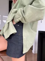 Campera verde claro de corte holgado y mangas largas con puños elásticos. Cierre frontal con botones a presión.