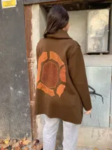 Saco marrón de lana Merino con cuello alto y cierre con broches tipo toggle.