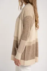 Cardigan abierto de punto con diseño de bloques de color en tonos beige, marrón y bordó. Presenta mangas largas, corte recto y bolsillos frontales aplicados.