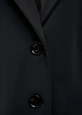 Blazer entallado de color negro con cuello de solapa, cierre frontal de tres botones y bolsillos delanteros con solapa. Presenta un diseño estructurado con detalles fruncidos en los laterales y forro interior.