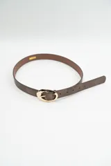 Cinturón de cuero sintético en tono marrón oscuro con acabado texturizado y hebilla ovalada de metal dorado con diseño irregular.