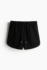 Short negro de felpa liviana, confeccionado en mezcla de algodón. Presenta cintura elástica con cordón ajustable y bolsillos laterales discretos.
