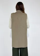 Chaleco largo color beige, con cuello solapa, un botón frontal y dos bolsillos de parche. Presenta costuras decorativas en contraste.