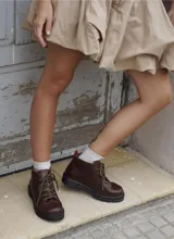 Borcego de cuero color marrón oscuro, con cordones jaspeados y suela de goma negra con plataforma dentada.