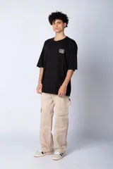 Remera de corte oversize color blanco, con cuello redondo y mangas cortas. Presenta un pequeño logo estampado en el pecho y un diseño gráfico grande en la espalda que incluye la frase 'Good Children' e ilustraciones de un ángel y llamas.