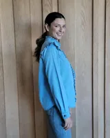 Camisa de denim azul con volados en el frente, cuello y hombros, de manga larga y corte clásico. Confeccionada en algodón.