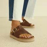 Sandalias de gamuza marrón con diseño de dedo, ajuste mediante hebilla metálica lateral y suela de plataforma de corcho con base de goma.