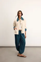 Sobrecamisa de algodón color beige, de corte holgado, con bolsillos frontales aplicados, cuello camisero y puños en contraste con estampado de cuadros en tonos verde oscuro. Cuenta con cierre frontal de botones metálicos.