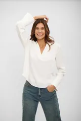 Blusa de color blanco con cuello en V y mangas largas con puños acampanados y detalle de frunces.