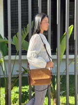 Cartera bandolera de cuero gamuzado color camel, con solapa frontal y cierre principal. Incluye dos correas desmontables, una corta y una larga regulable, y cuenta con bolsillo interior.