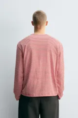 Camiseta de manga larga con ajuste relajado, cuello redondo y estampado de rayas horizontales en color rojo y blanco.