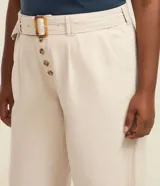 Pantalón recto de sarga color beige, con cierre frontal de botones y cinturón integrado con hebilla carey.