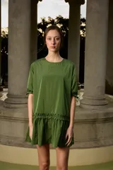 Vestido corto verde militar de nylon, con cuello redondo, mangas cortas con reguladores ajustables y detalle de volados fruncidos en la parte inferior.