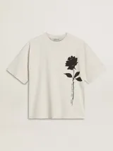 Remera color crema de corte holgado con estampa de una rosa negra en el lado derecho del pecho y texto en cursiva debajo de la flor.