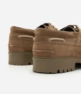 Zapato estilo náutico para hombre, confeccionado en cuero gamuza color marrón. Presenta diseño liso con puntera redondeada, costura aparente en la capellada, cordones bicolor y suela tractorada engomada.