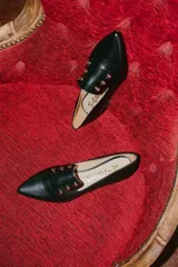 Chatitas negras de cuero con punta fina y apliques de tachas doradas.