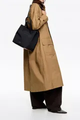 Bolso tote grande de color marrón, con asas de mano y asa bandolera regulable de tejido. Presenta un parche con el logo de Bimba y Lola en dorado en el frente.