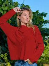 Buzo de punto color rojo con diseño calado en forma de V en el frente, cuello redondo y mangas largas.