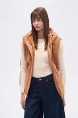 Chaleco negro sin mangas con capucha y cierre frontal. La parte superior es de tejido afelpado (tipo borrego o sherpa) y la parte inferior es de tejido acolchado liso.