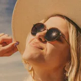 Lentes de sol Sunski modelo Baia Wire, con montura redonda color marrón y lentes color bronce polarizados.