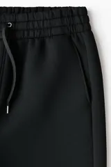 Pantalón tipo jogger de corte relajado con efecto neopreno, cintura elástica con cordón ajustable, bolsillos laterales al bies y bolsillo de parche en la parte trasera.