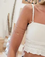 Brazalete de brazo tipo espiral en color dorado, con diseño minimalista de alambre fino y extremos redondeados.