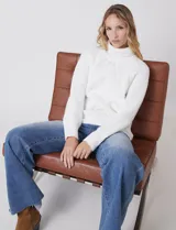 Polera de punto grueso color blanco, con cuello alto, mangas largas de corte ranglan y diseño de texturas combinadas.