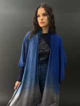 Ruana azul con degradé a gris, confeccionada en lana merino fina y suave, teñida artesanalmente. Presenta cuello plisado en fieltro de lana merino.