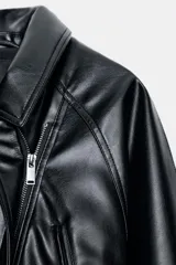 Cazadora de efecto piel con cuello solapa, manga larga con puños y cierre frontal con cremallera. Presenta bolsillos de vivo en el delantero y un cinturón de lazada en el mismo material para ajustar a la cintura.